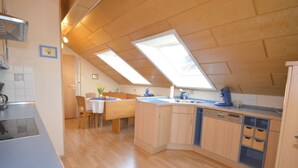 A kitchen with wooden cabinets, a dining table with chairs, and skylights. - Holiday Apartment ML Lafos (Konz)