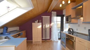 A kitchen with wooden cabinets, a built-in oven, and a window with a view. - Holiday Apartment ML Lafos (Konz)