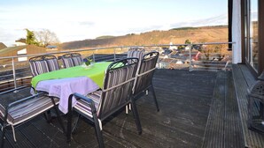 A balcony with a table set for two, overlooking a scenic landscape. - Holiday Apartment ML Lafos (Konz)