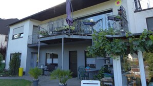 A two-story building with a balcony, outdoor seating area, and potted plants. - Holiday Apartment ML Lafos (Konz)