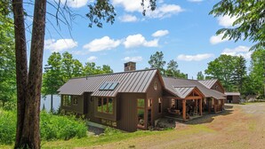 A cabin with a metal roof, large windows, and a porch area. - Schoolmarm Rock - 450' of private waterfront on Rangeley Lake (Rangeley)