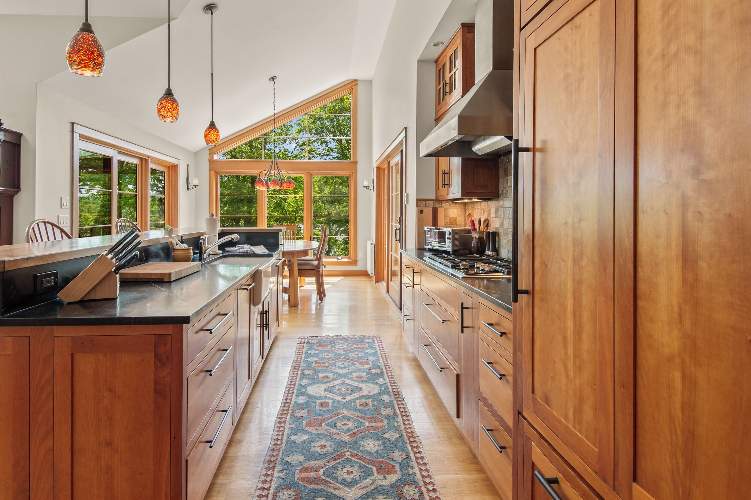 A modern kitchen with wooden cabinets, a central island, and pendant lighting.