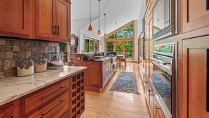 A spacious kitchen with wooden cabinets, a marble countertop, and a large island. - Schoolmarm Rock - 450' of private waterfront on Rangeley Lake (Rangeley)