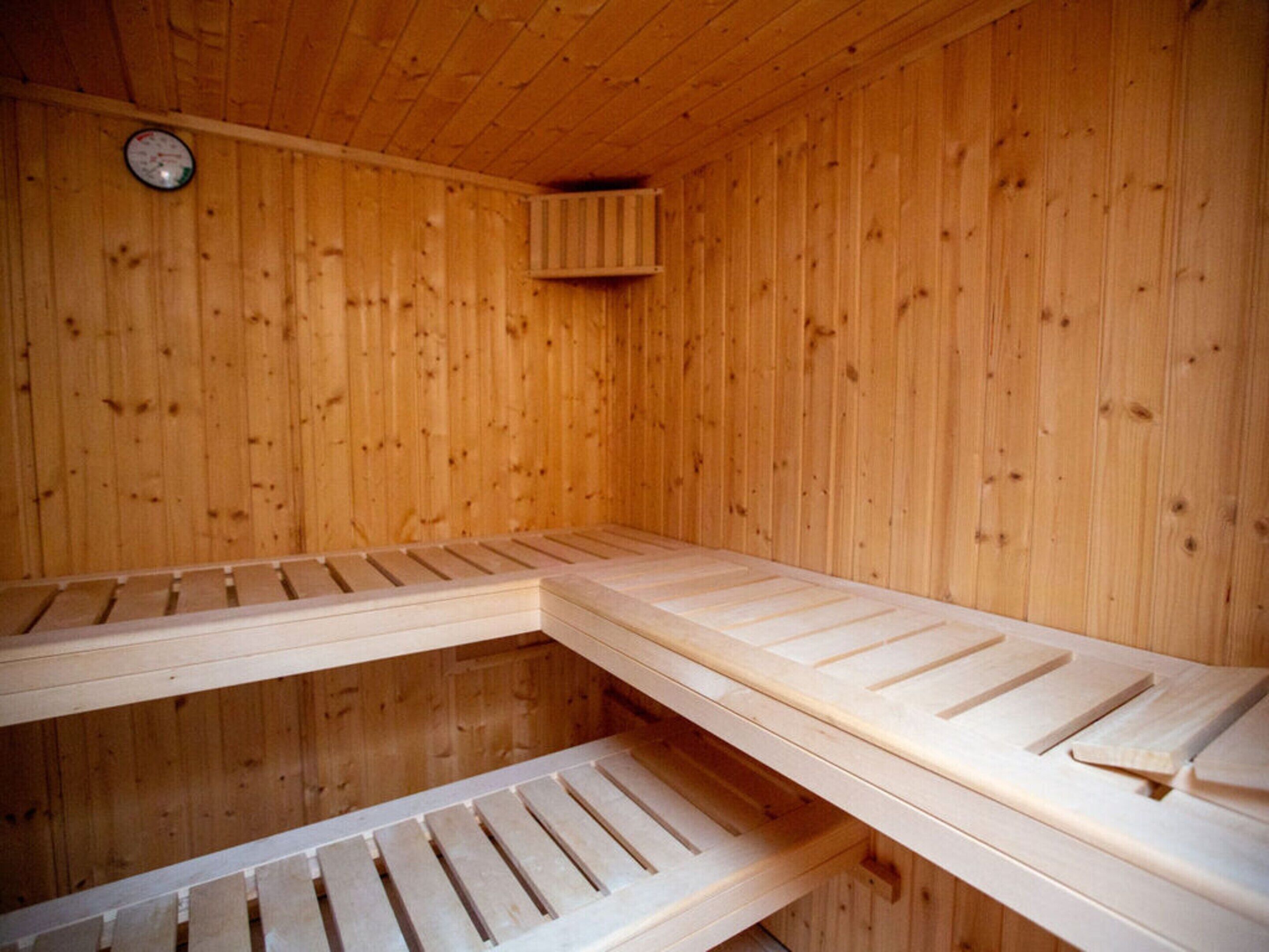 A sauna with wooden benches and a visible thermometer on the wall.