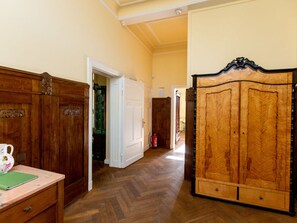Un couloir aux murs lambrissés, une armoire en bois et un bureau sur lequel se trouve un carnet vert.