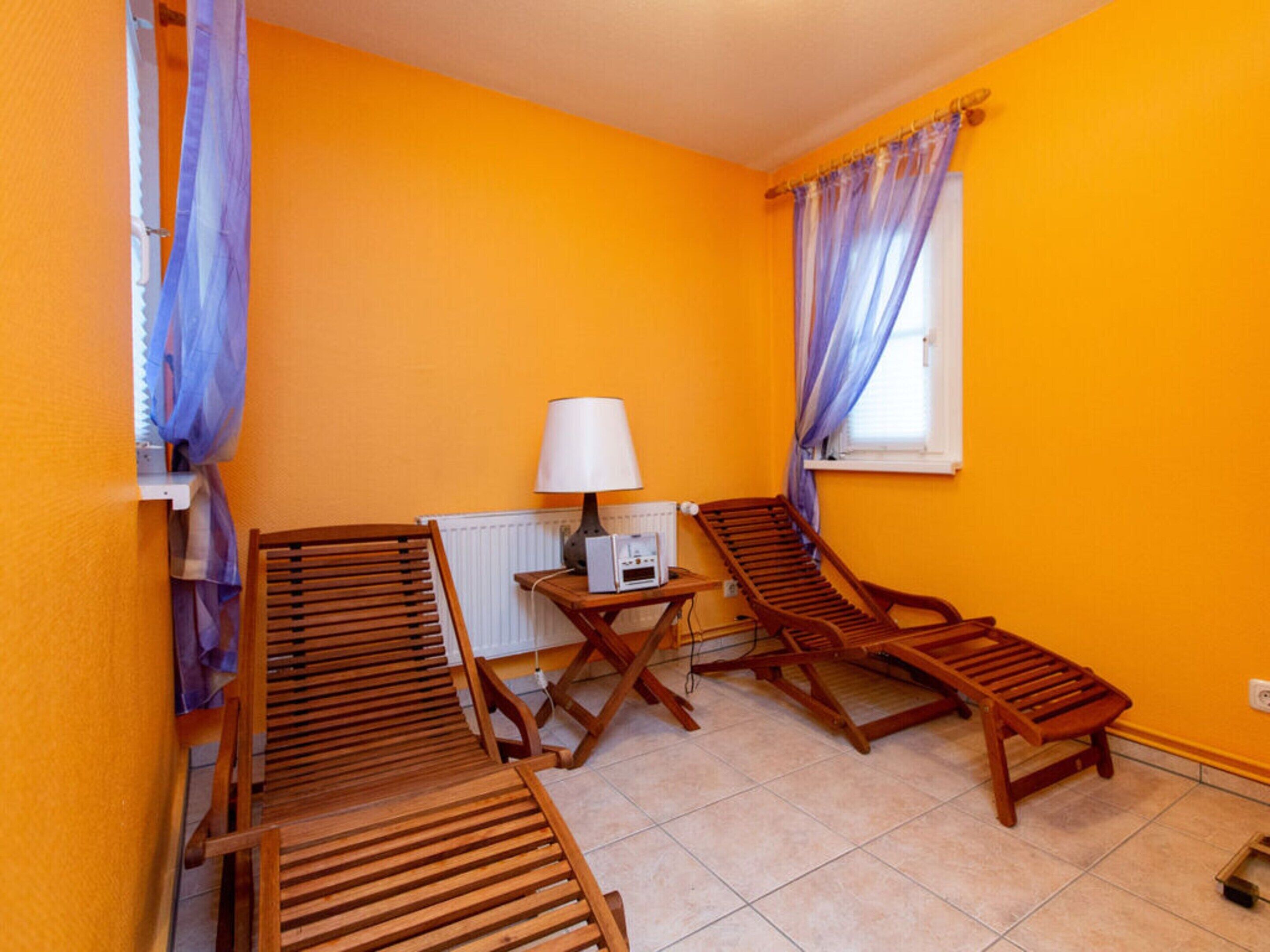 Een kamer met twee houten fauteuils, een bijzettafeltje met een lamp en een radiator.