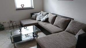 A modern living room with a sectional sofa, a glass coffee table, and a small side table. - Rednak Modern Retreat (Polch)