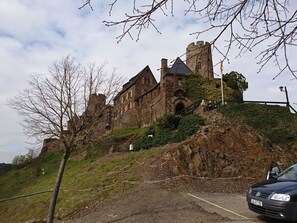 A historic castle with multiple towers and a prominent entrance, surrounded by a hilly landscape. - Rednak Modern Retreat (Polch)