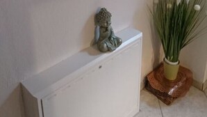 A white cabinet with a Buddha statue on top, a painting of a Buddha with candles, and a vase with white flowers. - Rednak Modern Retreat (Polch)