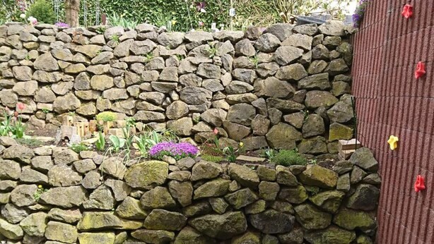 A stone wall with plants and a wooden deck. - Rednak Modern Retreat (Polch)