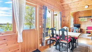 A wooden cabin with a dining area, a TV, and a view of the outdoors.
