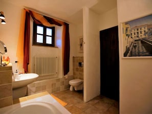 A bathroom with a bathtub, toilet, and a radiator.