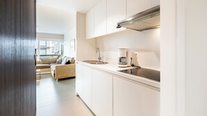 A modern kitchen with white cabinets, a stainless steel range hood, and a coffee maker. - Family Stay in Oostduinkerke (Koksijde)