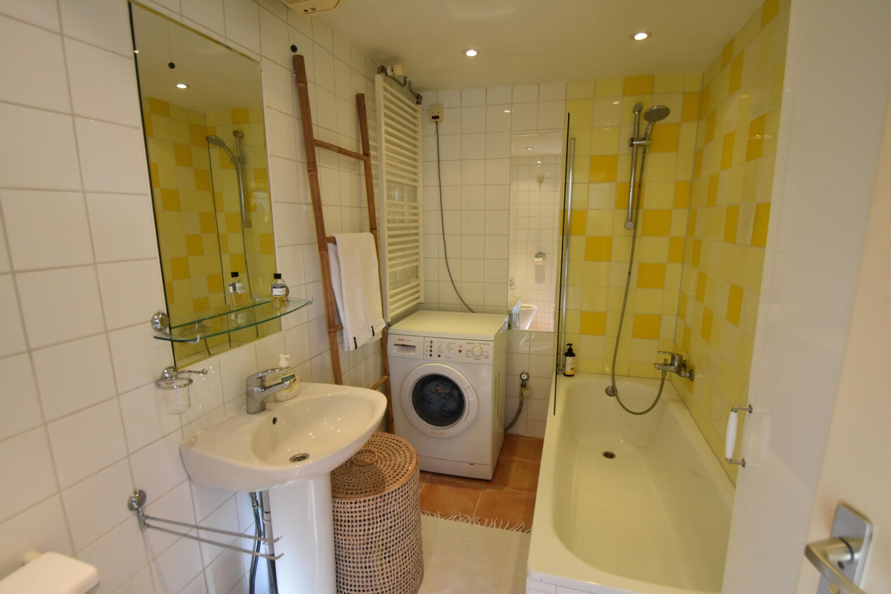 Un baño con lavamanos, lavadora y bañera.
