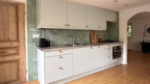 A kitchen with white cabinets, a green backsplash, and wooden flooring.