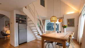 A modern kitchen with a built-in fridge, wooden dining table, and a staircase leading to an upper level.