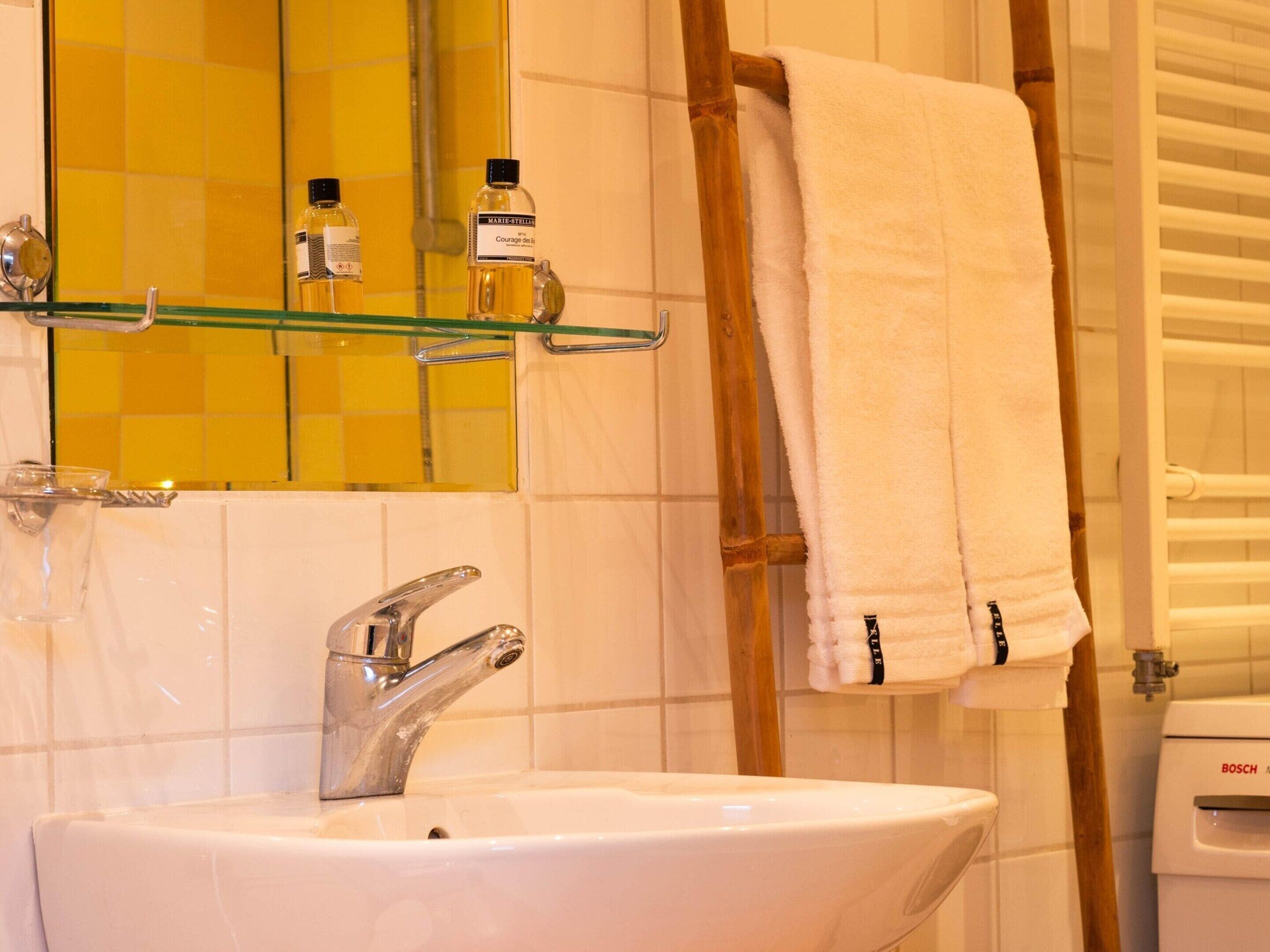 Une salle de bain avec un lavabo blanc, un miroir et un porte-serviettes.