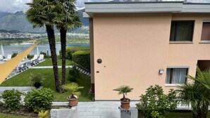 A building with a beige exterior, a concrete staircase leading to a door, and a view of a lake and mountains in the background. - Holiday Apartment Casa Chimp 6 (Gambarogno)