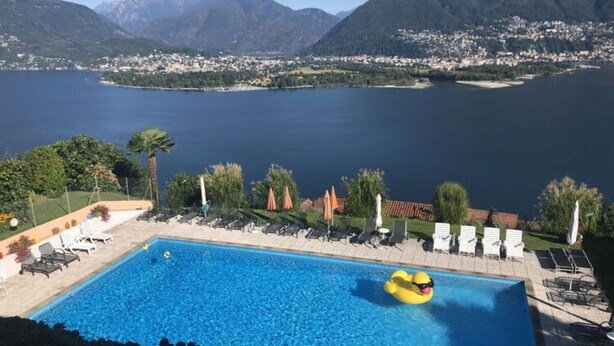 A swimming pool with a view of a lake and mountains in the background. - Holiday Apartment Casa Chimp 6 (Gambarogno)