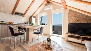 A modern kitchen with a dining area, a TV, and a balcony with a view. - Apartments Bella Vista - One Bedroom Apartment With Sea View (Kastav)