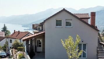 A two-story house with a balcony, a view of a lake, and a mountain in the background.