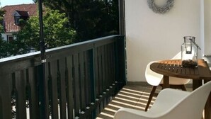 A balcony with a wooden railing, a white chair, a small table with a glass container, and a hanging wreath. - Holiday Apartment Summit Nest (Braunlage)