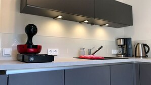 A modern kitchen with grey cabinets, a black coffee machine, a red electric kettle, and a black electric kettle on the counter. - Holiday Apartment Summit Nest (Braunlage)