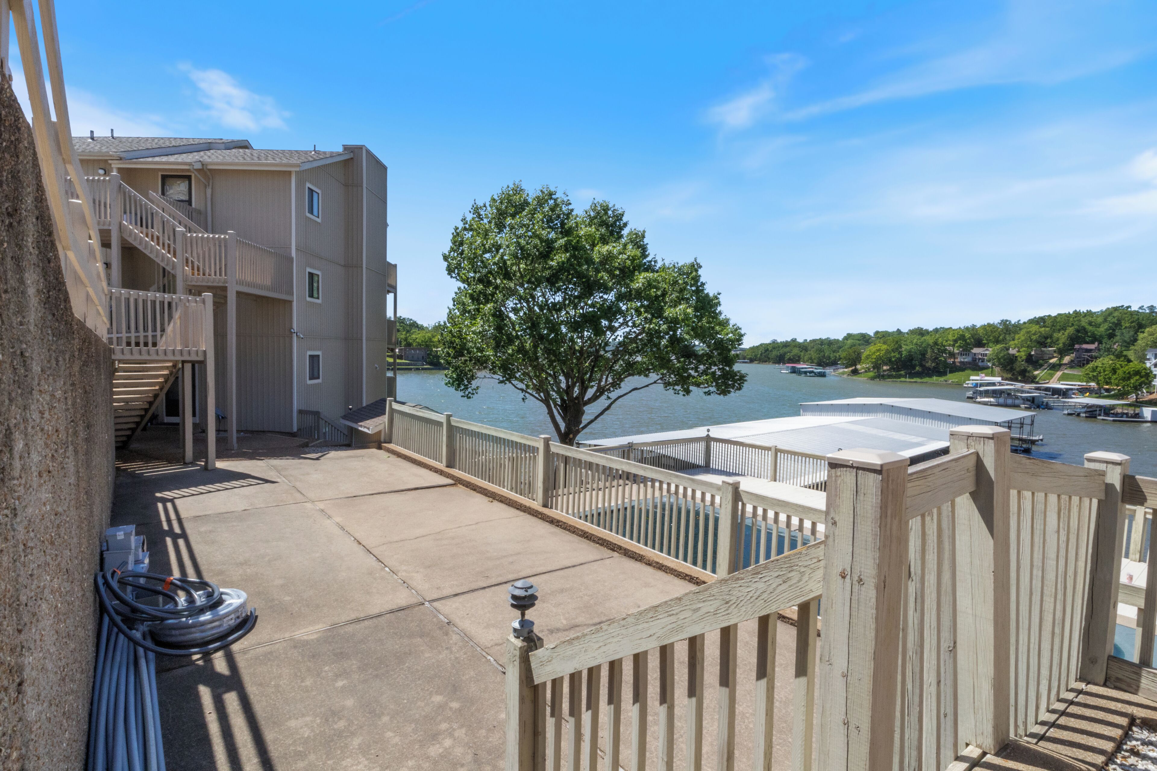 A waterfront property with a wooden deck, a staircase leading to a building, and a view of the water.