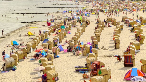 A beach with numerous sun loungers and umbrellas, a pier in the background, and a crowd of people. - "residential Residence" Modern Retreat (Kellenhusen)