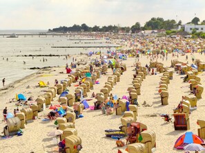 A beach with numerous sun loungers and umbrellas, a pier in the background, and a crowd of people. - "residential Residence" Modern Retreat (Kellenhusen)