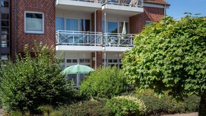 A multi-story building with a brick facade, balconies, and a green umbrella in the foreground. - "residential Residence" Modern Retreat (Kellenhusen)