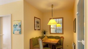 A compact dining area with a wooden table and chairs, a hanging lamp, and two framed artworks on the walls. - "residential Residence" Modern Retreat (Kellenhusen)