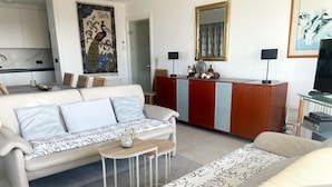 Un salon moderne comprenant un canapé, une table basse, un meuble et un téléviseur.