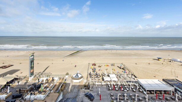 A beachside hotel with a long pier, beach umbrellas, and a view of the ocean. - Apartment Next to the Casino (Blankenberge)