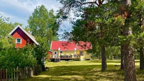 A red-roofed house with a wooden deck and a fenced yard. - 7 Person Holiday Home in Hogsby (Högsby)