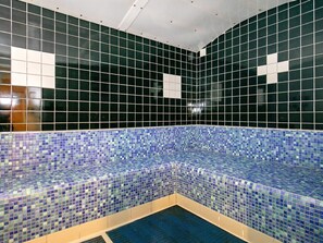 Zona de piscina con baldosas, borde de mosaico azul y techo blanco.