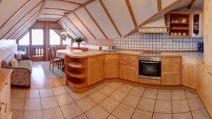 Eine kompakte Küche mit Holzausziehtüren, einem eingebauten Backofen und einer gefliesten Spritzschutzwand.