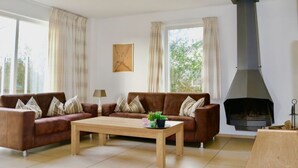 A living room with two brown sofas, a wooden coffee table, and a fireplace. - 158-type 4l1- Strand Park (De Koog)