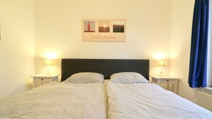 A double bed with two bedside tables, each with a lamp. There is a framed picture above the bed. - 158-type 4l1- Strand Park (De Koog)