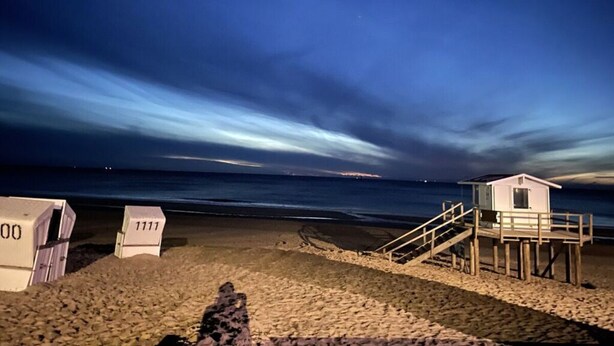A beach with a lifeguard tower and a wooden staircase leading to it.
