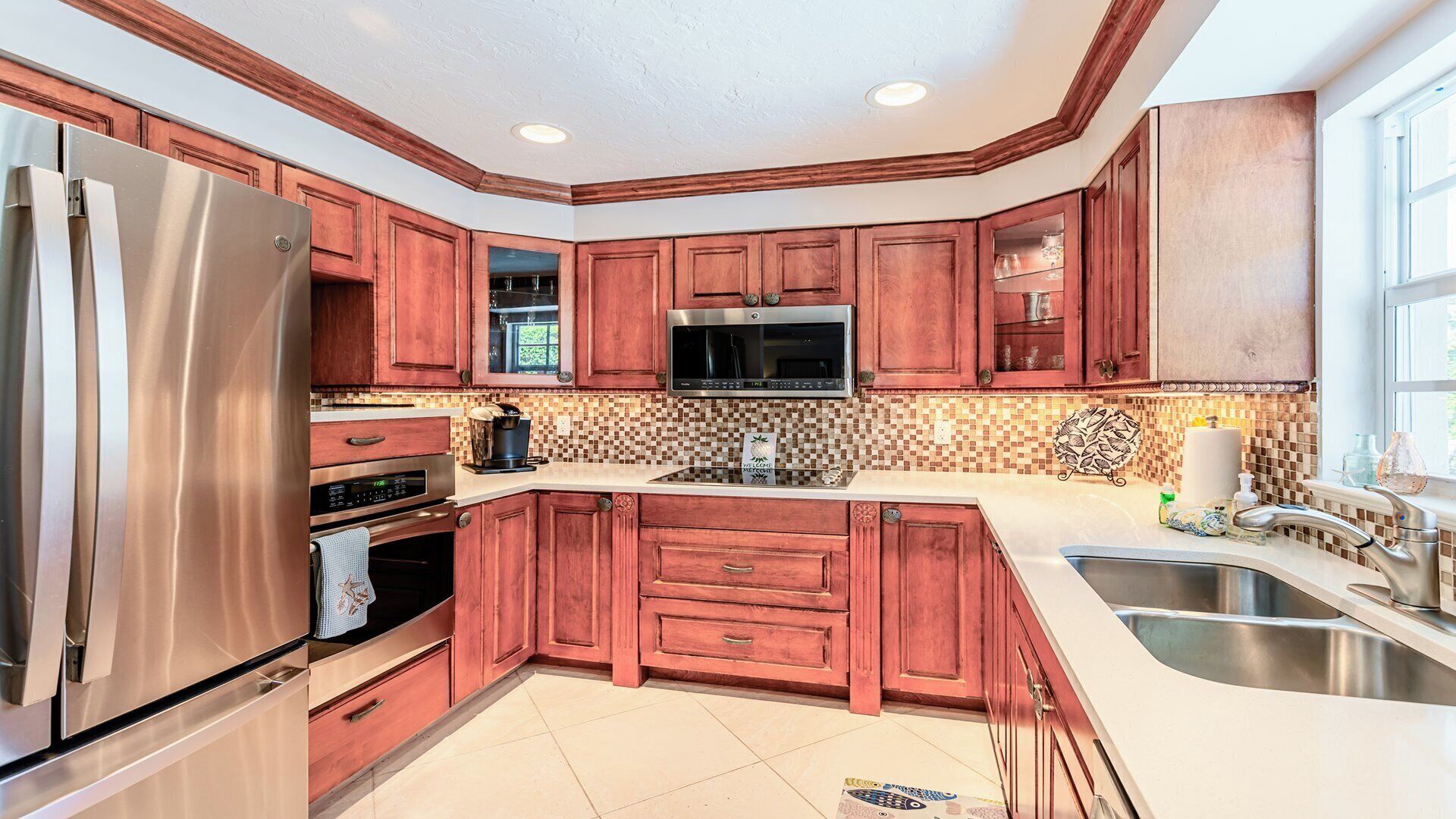 A modern kitchen with wooden cabinets, stainless steel appliances, and a tiled backsplash.