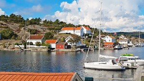 A marina with boats docked, a white building with a red roof, and a flag on a flagpole. - 12 Person Holiday Home in Lyngor (Tvedestrand)