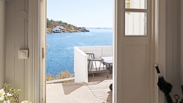A room with a view of the sea, a small outdoor seating area, and a white door. - 12 Person Holiday Home in Lyngor (Tvedestrand)