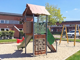 Un parque infantil con un juego de escalada, toboganes y columpios.