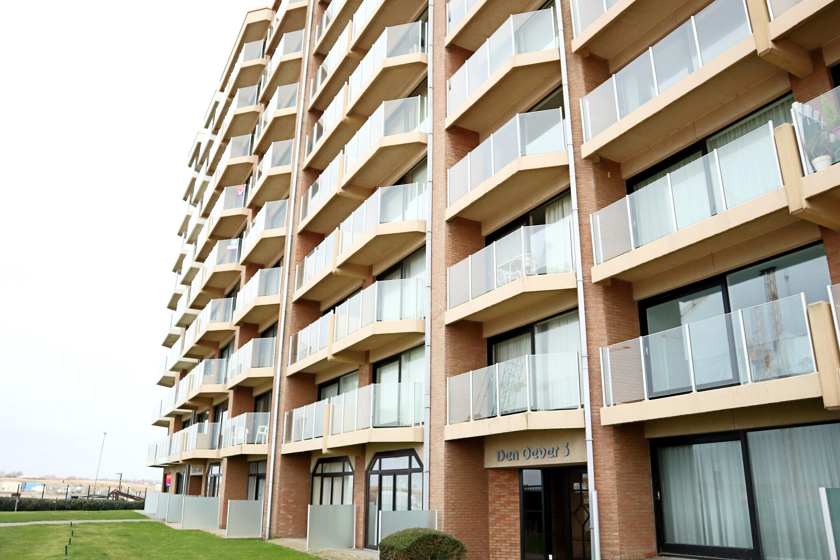 A multi-story residential building with balconies, a brick facade, and a sign reading "Den Oever 3".