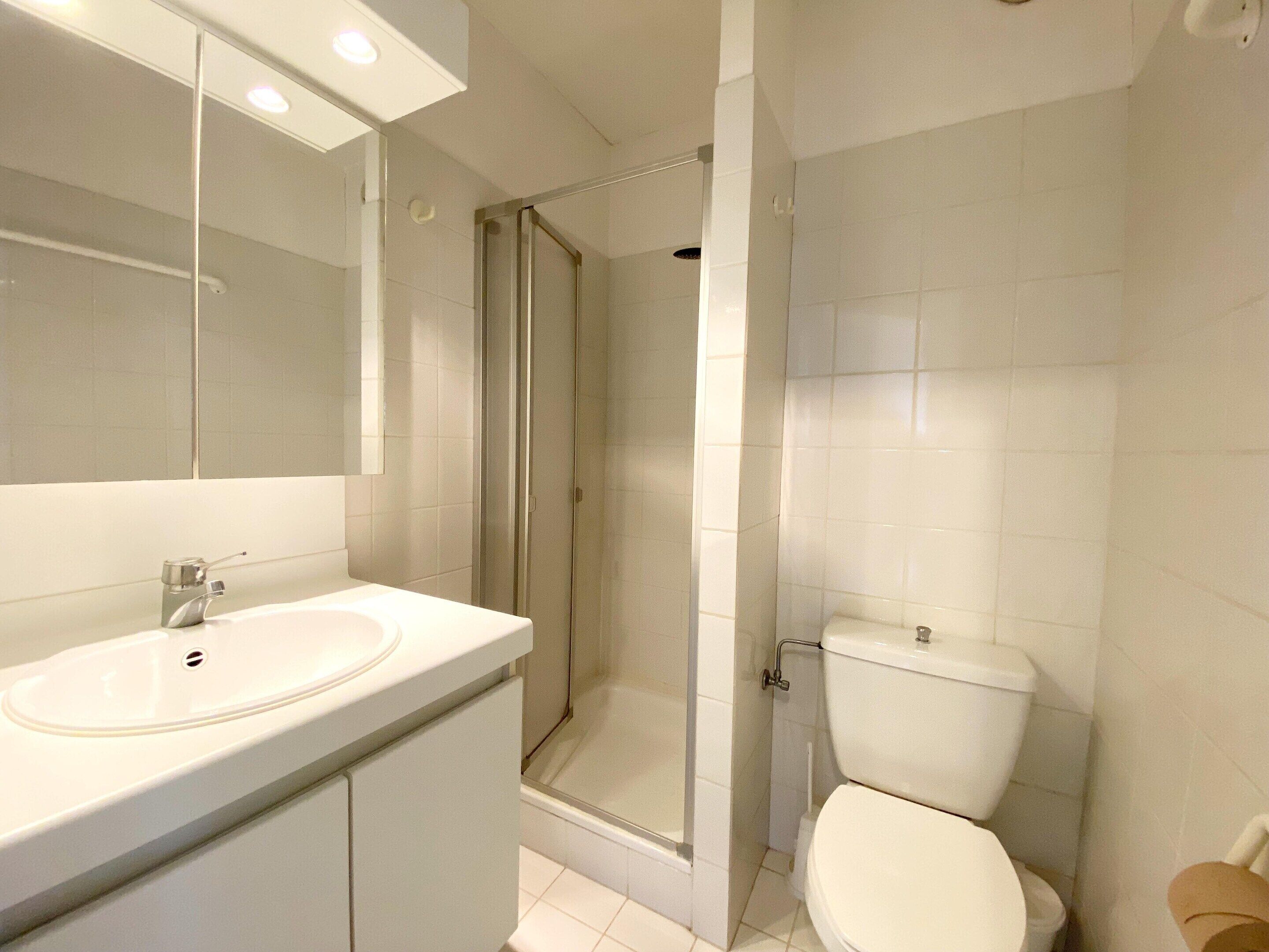 Une salle de bain avec un lavabo blanc, un miroir et des toilettes.