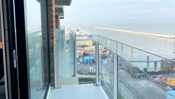 Ein Balkon mit Blick auf einen Hafen und einen langen Steg, der sich ins Wasser erstreckt.