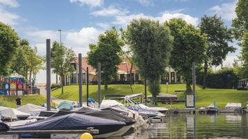 A marina with boats docked, a playground, and a grassy area with trees.