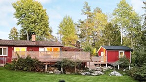 A red cabin with a wooden deck and a small shed, surrounded by a grassy yard and trees. - 8 Person Holiday Home in Brottby-by Traum (Brottby)