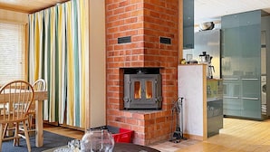 A modern living room with a brick fireplace, wooden flooring, and a dining area with chairs. - 8 Person Holiday Home in Brottby-by Traum (Brottby)
